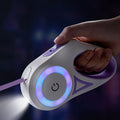 Hand holding a led dog leash with glowing elements against a dark background
